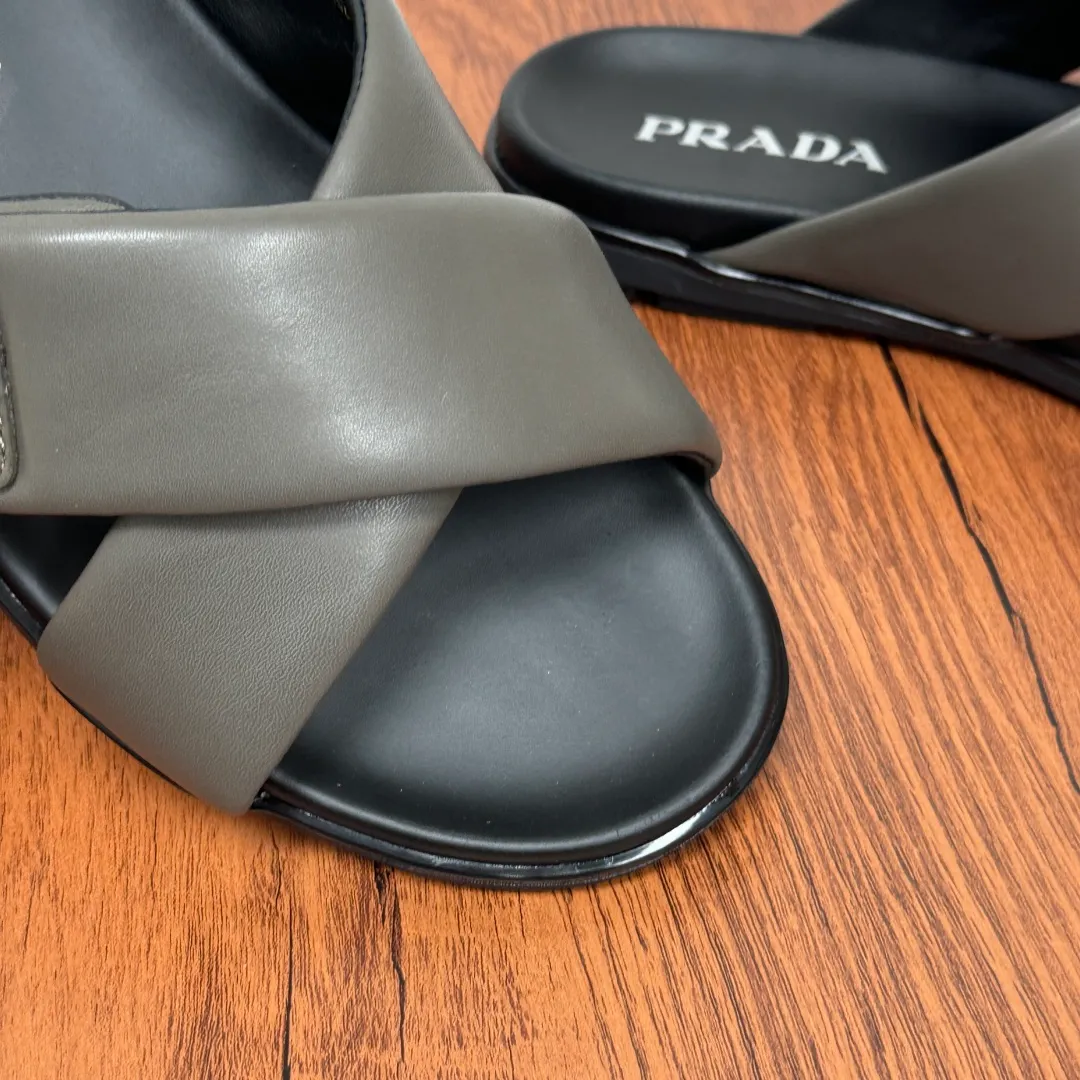 Batch 580 Prada/Prada's new men's leather cross slippers. Velcro closure can finely adjust the size. Calf leather light luxury slippers. Thick soft calf leather wraps the upper. Fat but soft rubber lazy style, soft and comfortable, excellent foot feel. Genuine leather bottom layer, cross style, with a Velcro closure buckle, easy to adjust the appropriate size, and a perfect fit for the wearing experience. The enamel gold triangle logo highlights the brand's classic features. Lightweight rubber thin sole, high foot comfort! Complete package! Size: 39-40-41-42-43-44-45 Leather shoe size Item number: 2X7132 Gray